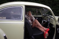 a woman sitting in the back seat of a volkswagen beetle