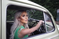 a woman sitting in the driver's seat of an old car