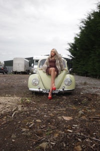 a woman sitting on top of a vw beetle